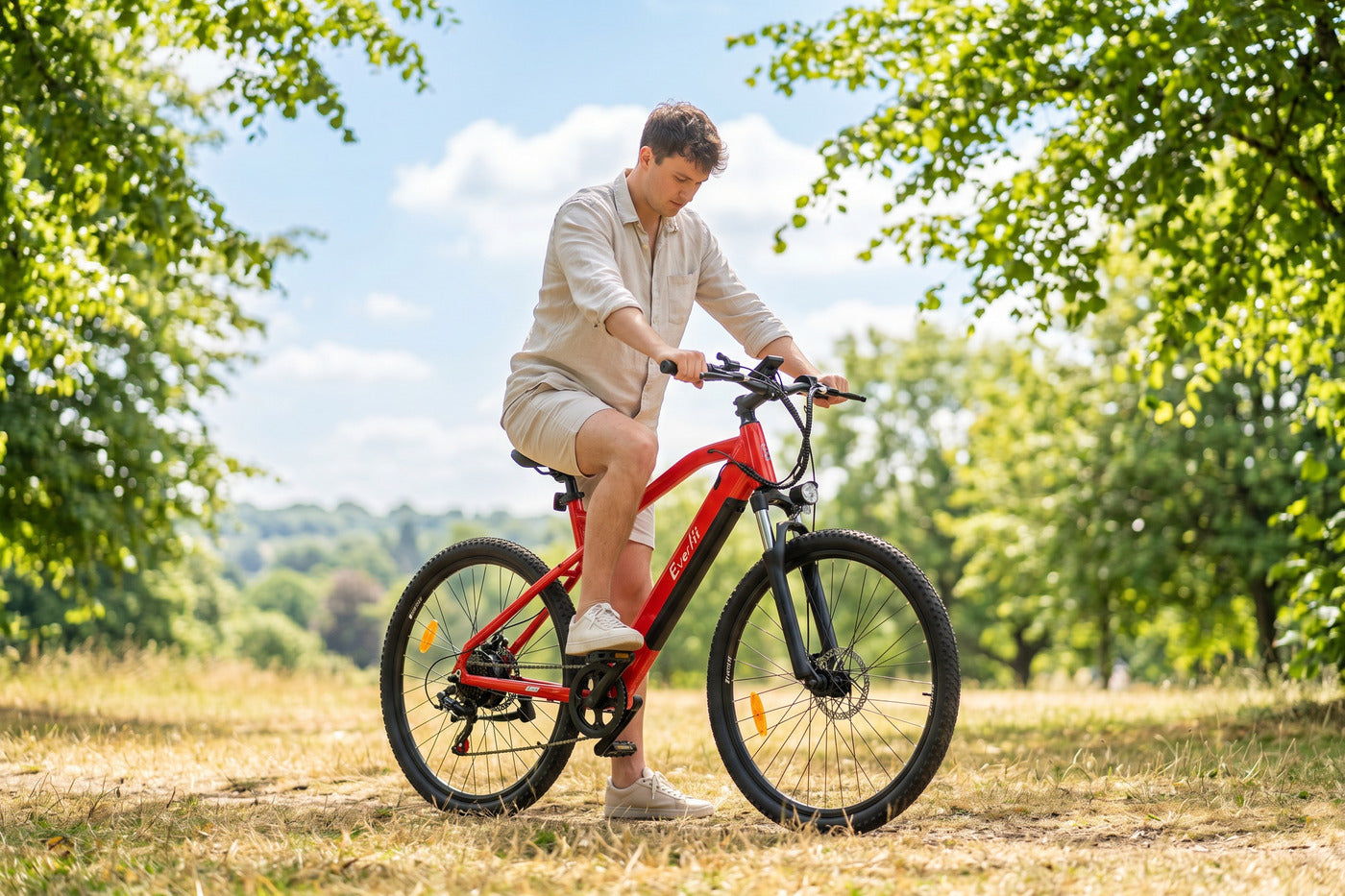 Rider checking the fit of a red Everfit mountain electric bike in a sunny British park