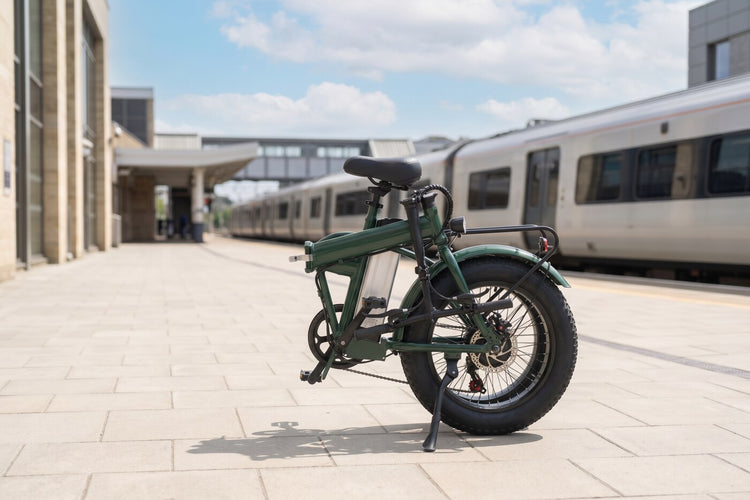 Green folding electric bike on a sunny British railway station platform in summer